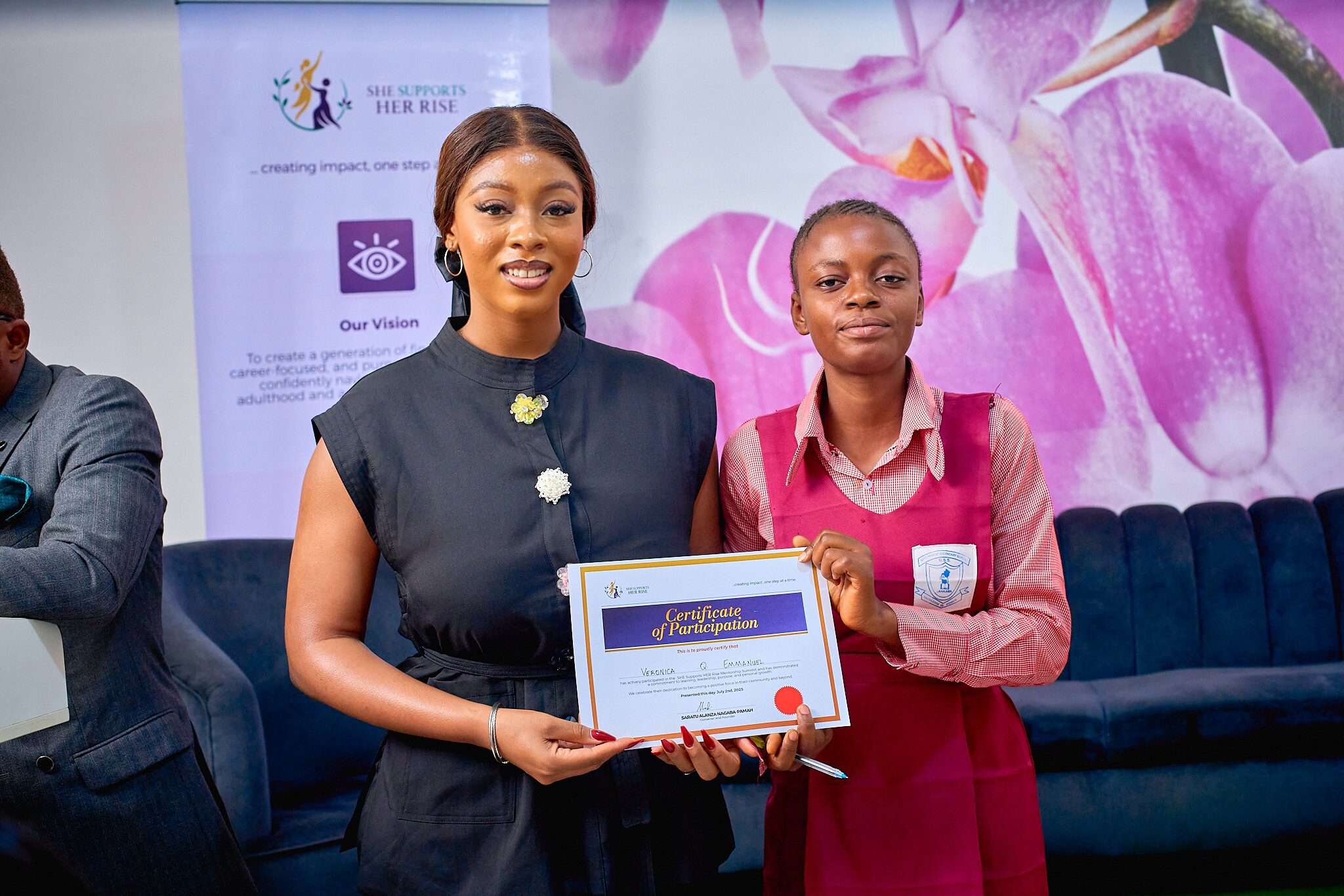 Anna giving a certificate to a secondary school student at the She Supports Her Rise NGO event