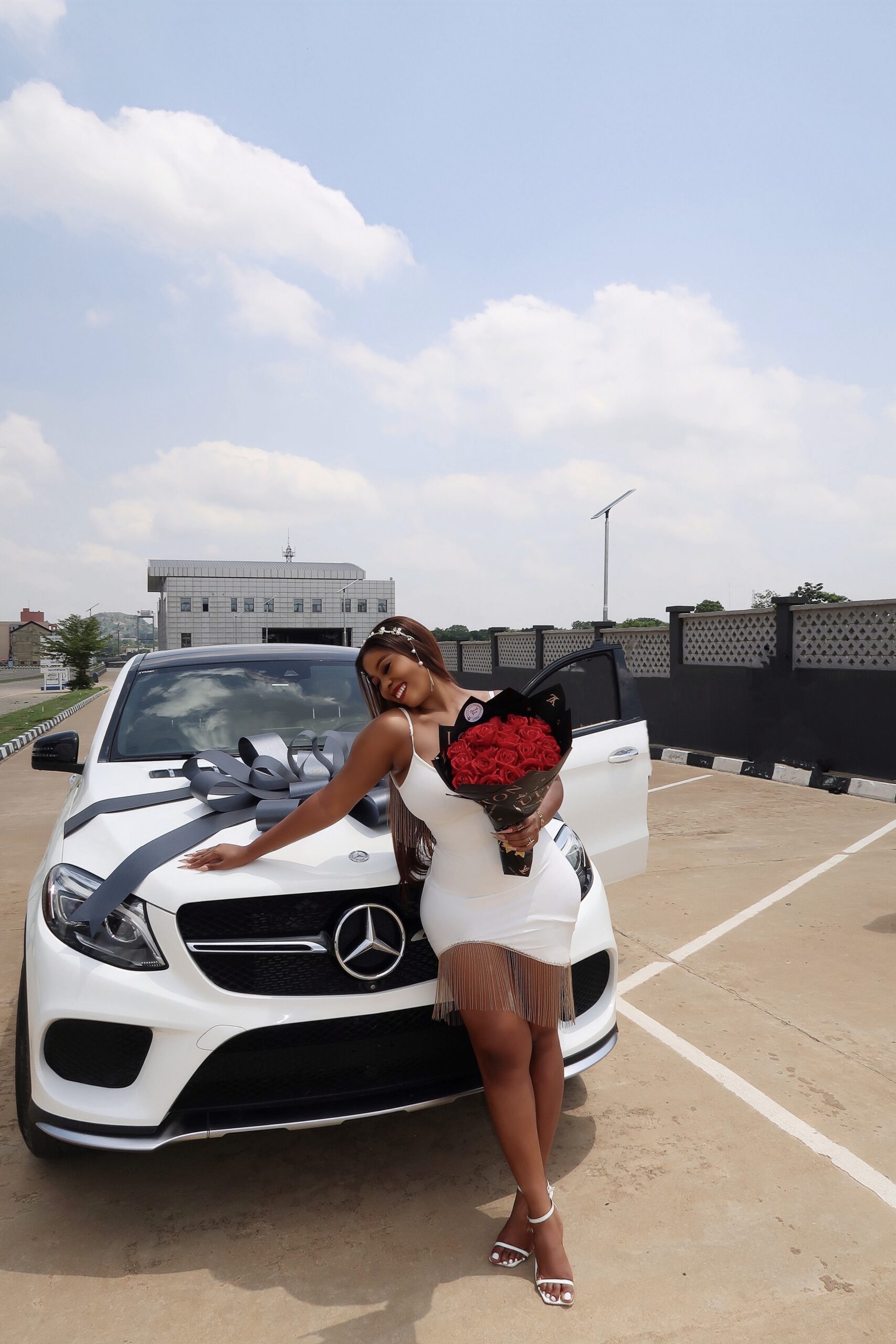Anna with her white Mercedes Benz GLE Coupe and a bouquet of roses
